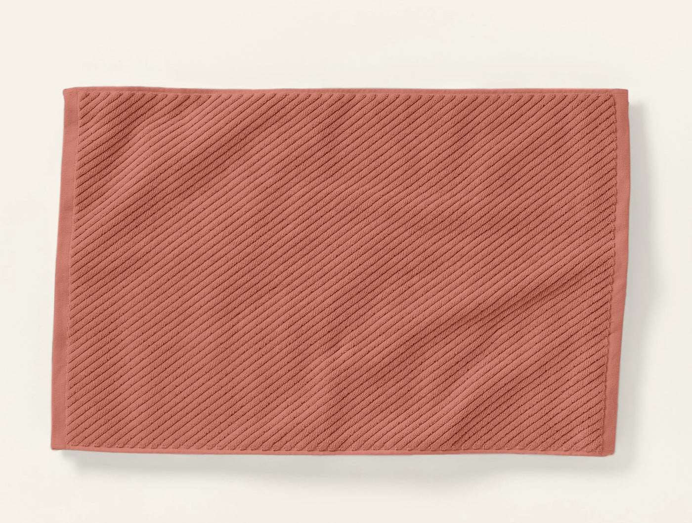 Terracotta twill-weave bath rug laid flat, showing diagonal ribbed texture.