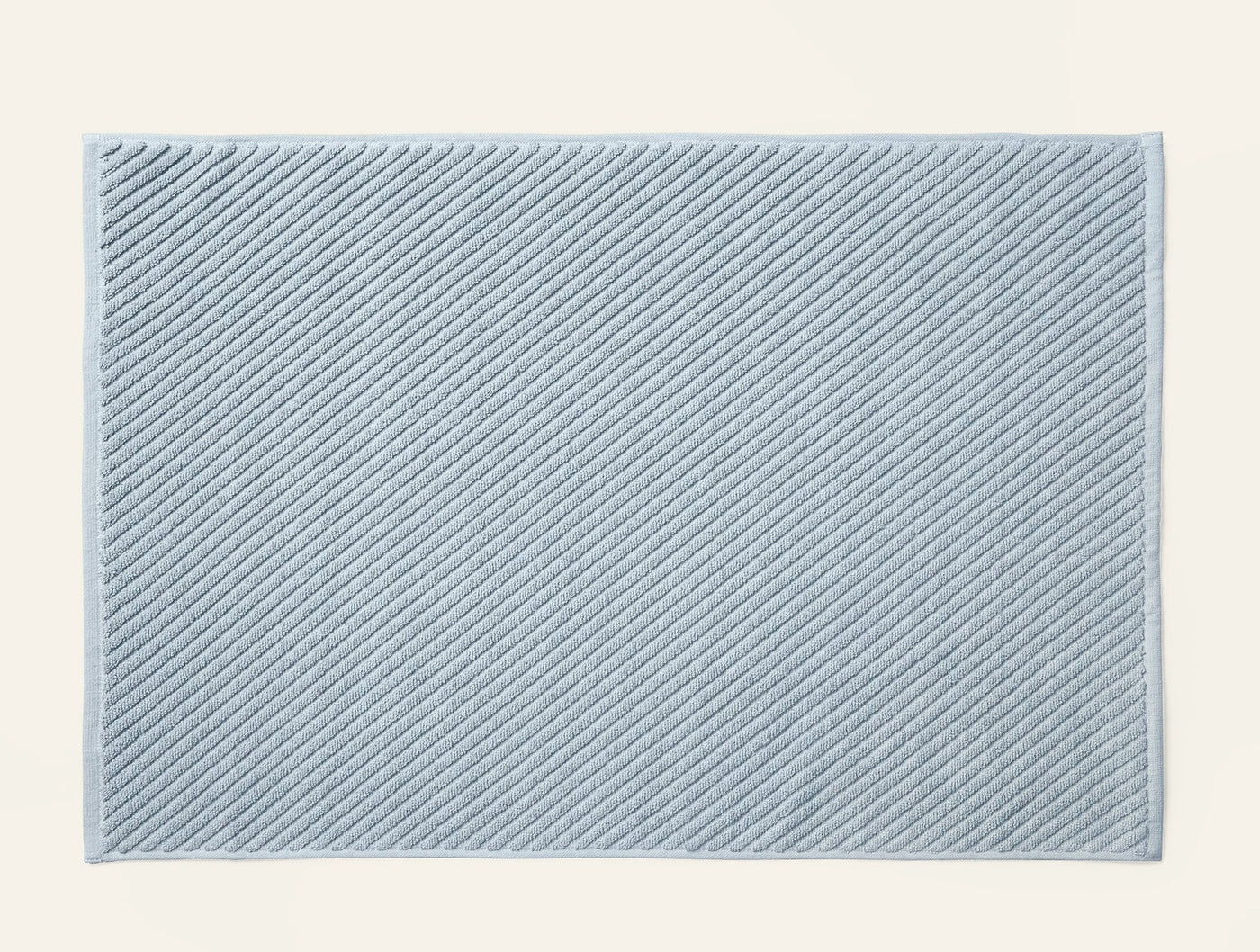 Close-up of Coyuchi Air Weight bath rug in pale blue with diagonal ribbed twill texture.