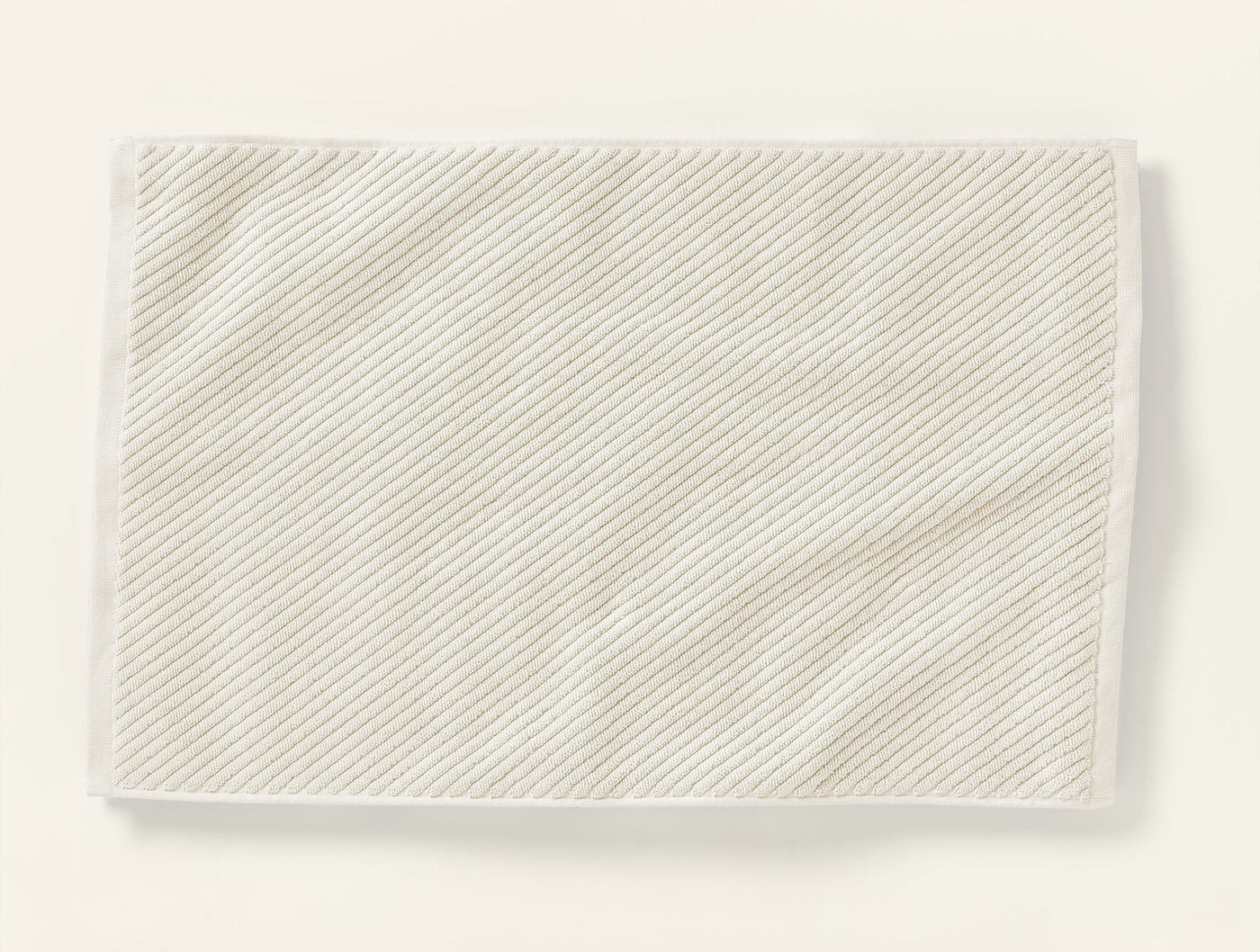 Close-up of Coyuchi Air Weight bath rug showing diagonal twill stripe weave in ivory.