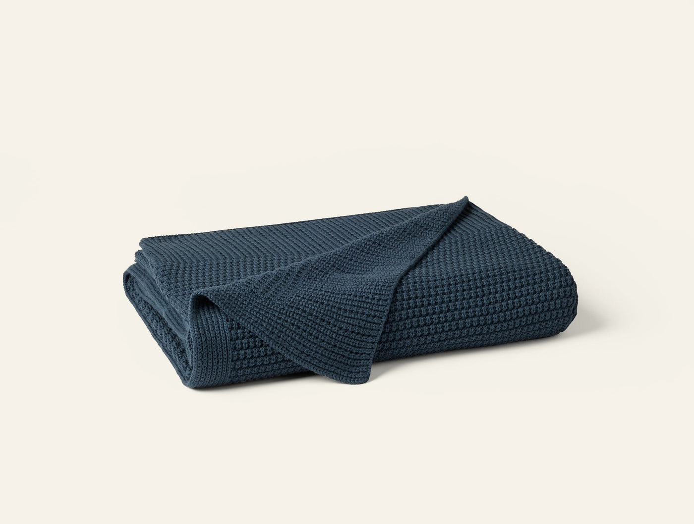 Coyuchi Avalon Knit Throw folded, showing waffle-knit texture in deep navy blue.