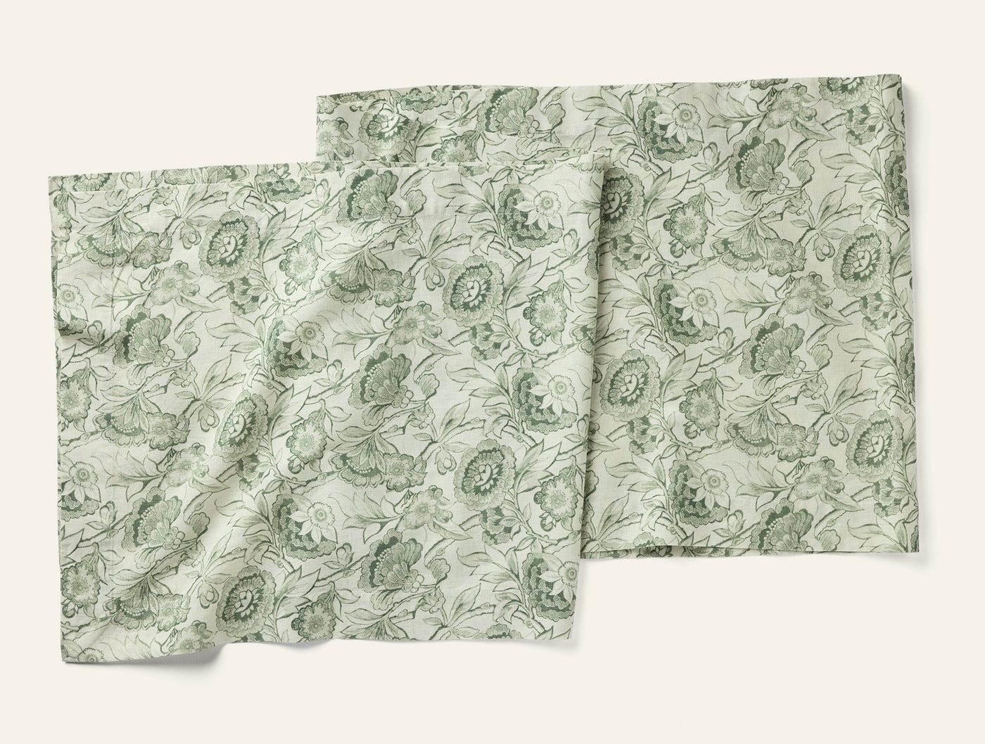 Coyuchi Balboa Print table runner in sage green floral botanical pattern, two pieces overlapping.
