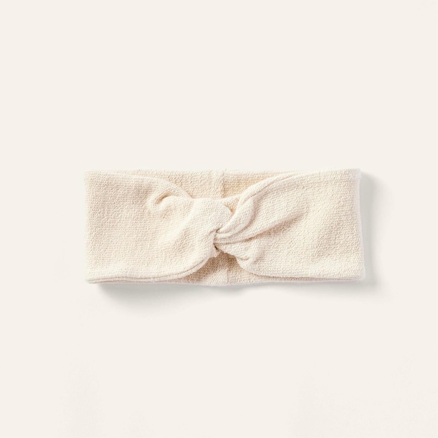 Coyuchi Bare headband in ivory terry cloth with a knotted front detail, flat lay.