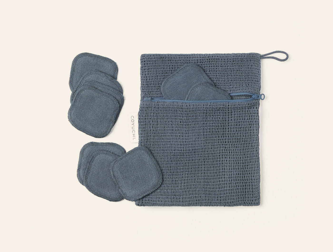 Coyuchi Bare makeup pads in slate blue with waffle-weave storage pouch, flat lay.