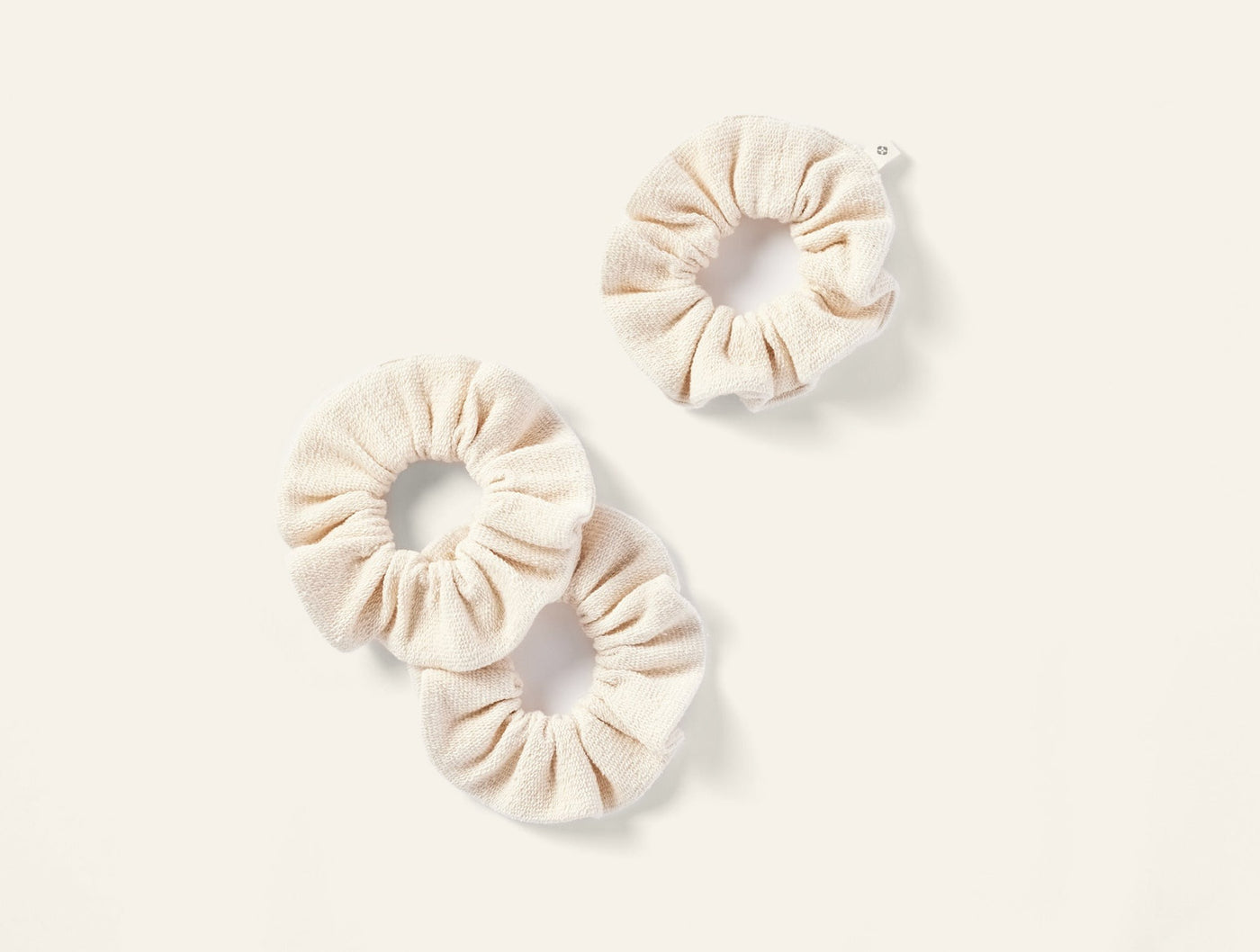 Coyuchi Bare scrunchie set of three, ivory textured linen fabric on white background.