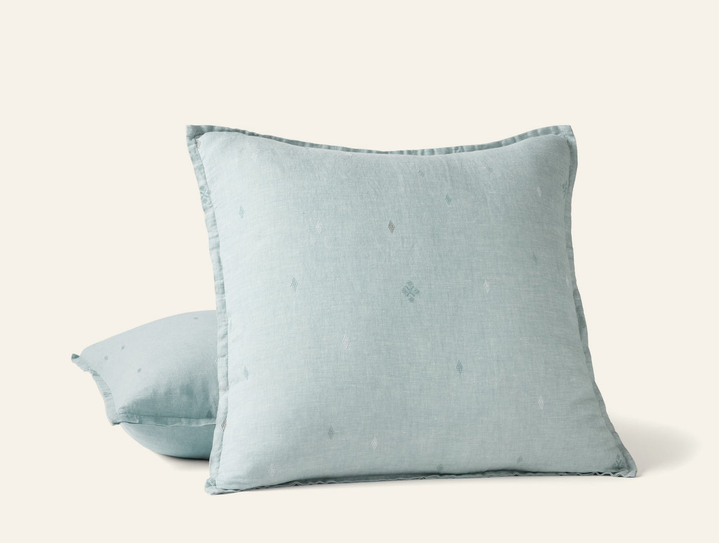 Two Coyuchi Cambria linen pillows stacked, pale aqua with subtle embroidered dot motif.