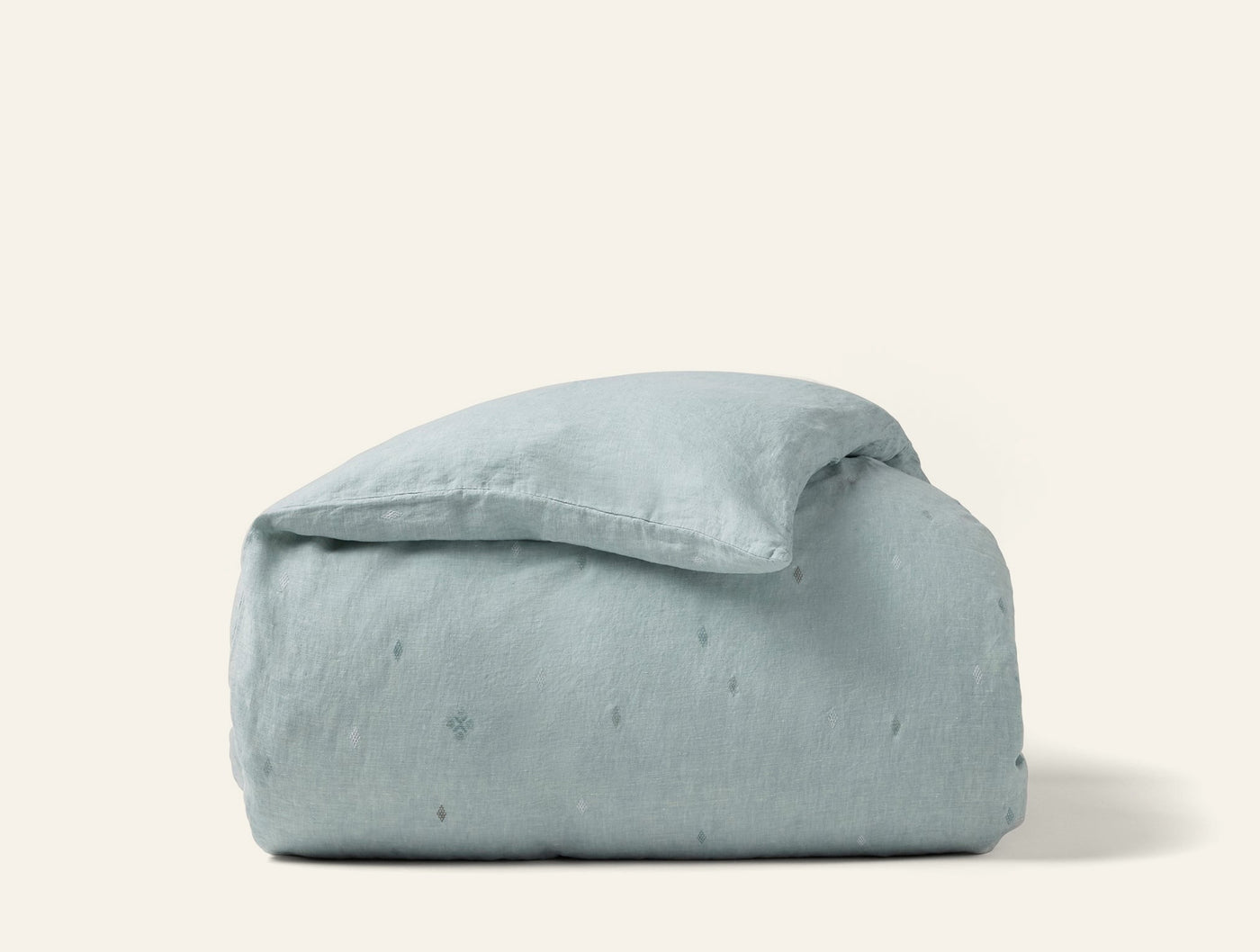 Cambria duvet cover folded compactly, showing sage linen with subtle embroidered dot detail.