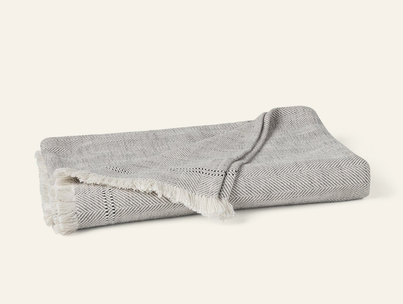 Coyuchi Canyon throw in grey herringbone weave with ivory fringe trim, folded flat.