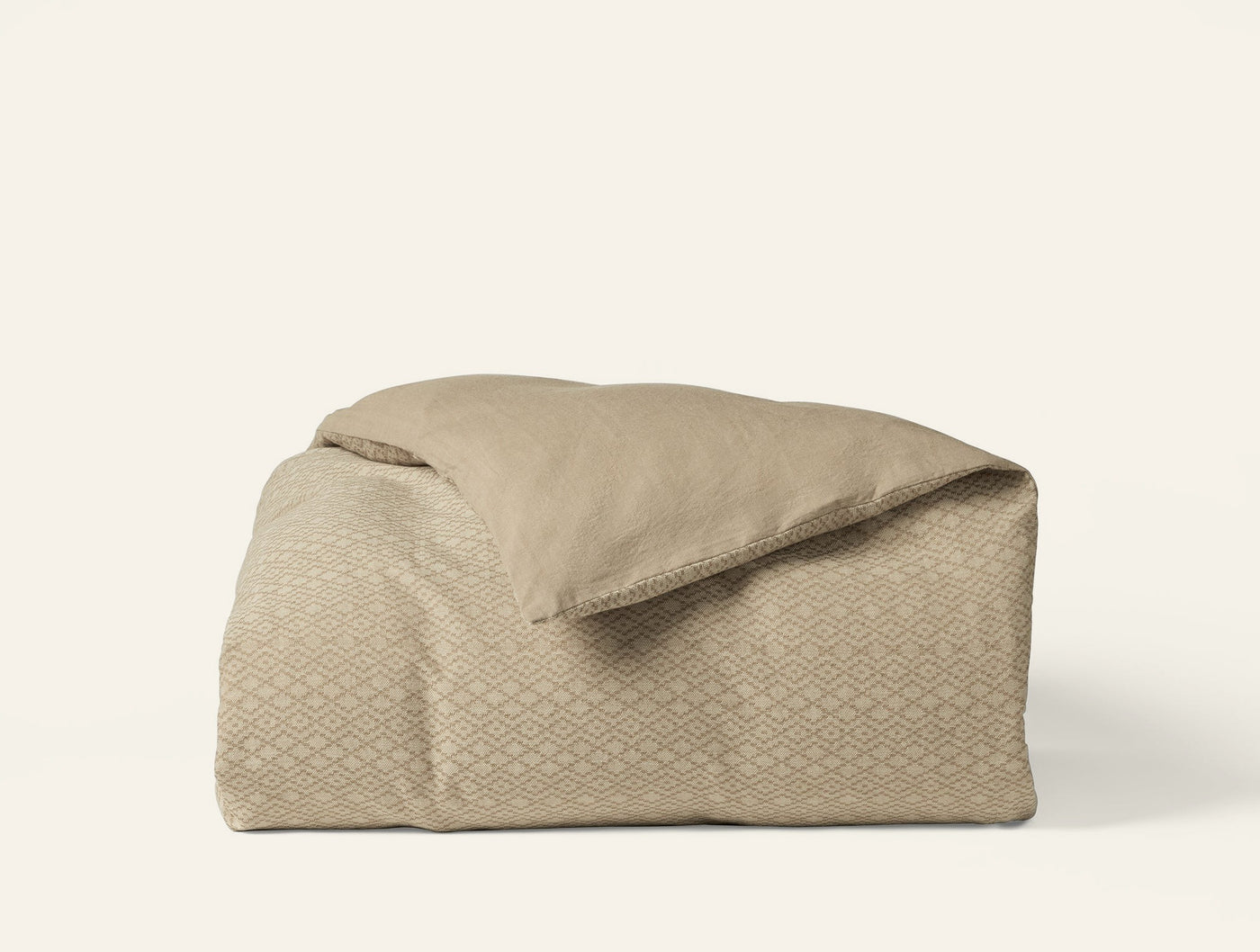 Close-up of Coyuchi Capitola duvet cover in taupe with woven diamond pattern, neatly folded.