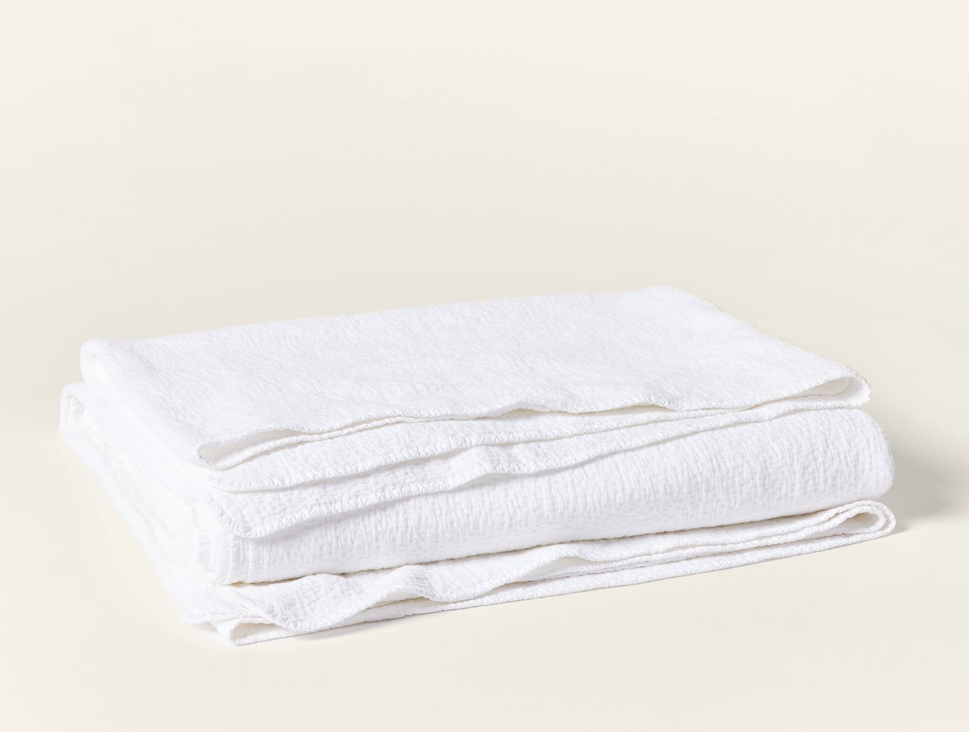 Coyuchi Cascade Matelasse blanket in white, neatly folded showing textured weave.