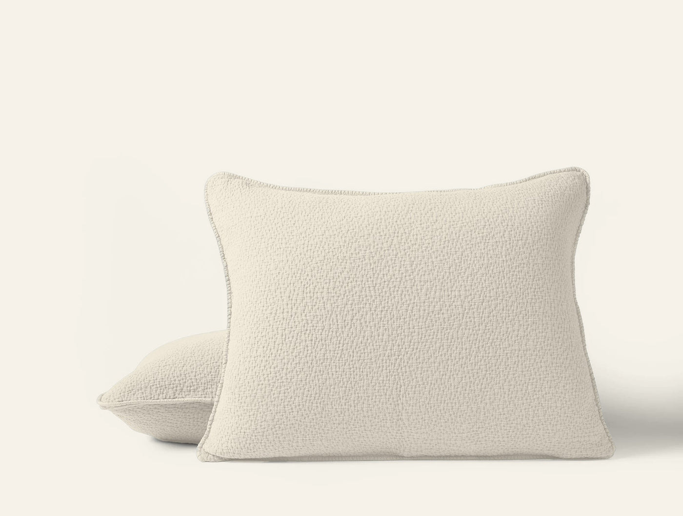Pair of Coyuchi Cascade Matelassé shams in ivory, boucle-textured fabric, stacked view.