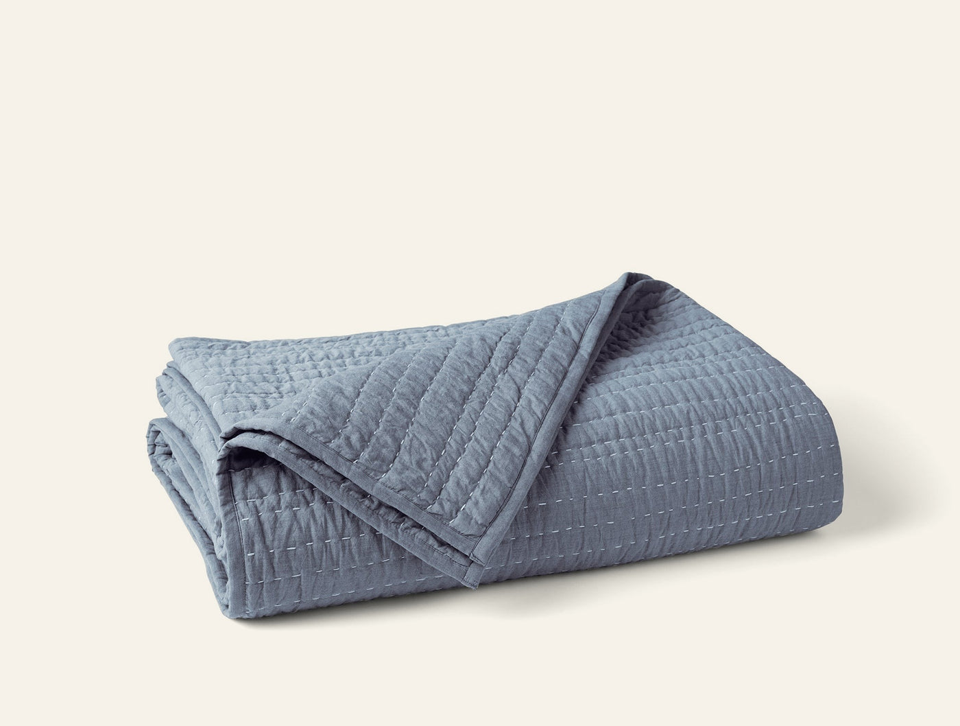 Coyuchi Channel Handstitched quilt folded, slate blue with vertical channel quilting detail.