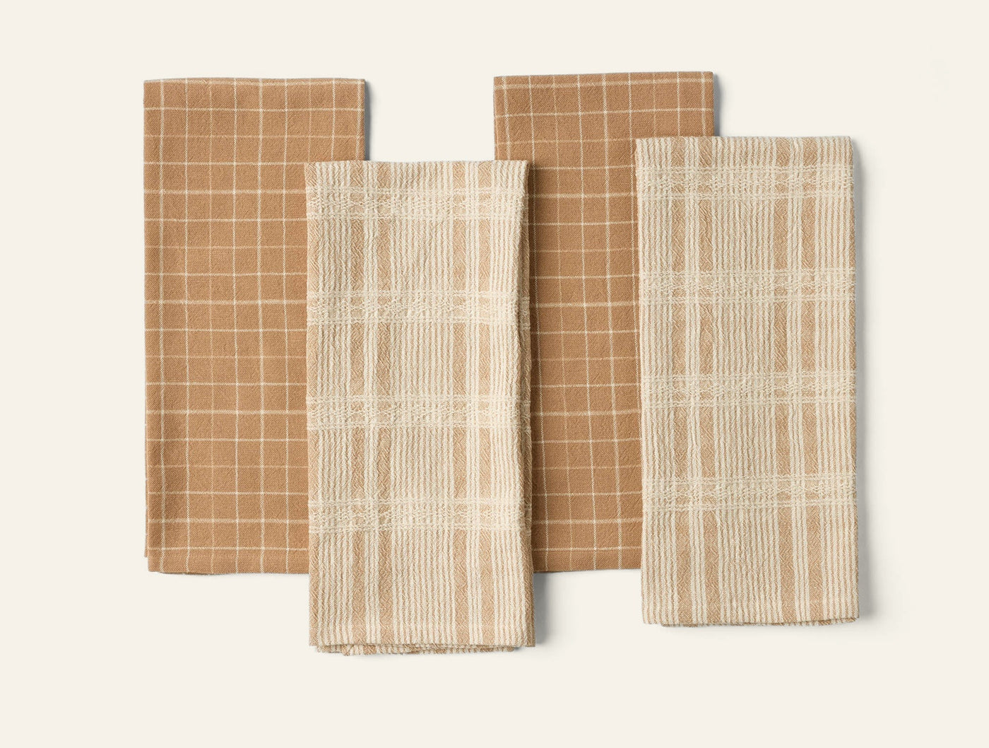 Coyuchi Clarendon kitchen towels in caramel and ivory plaid patterns, set of four folded flat.