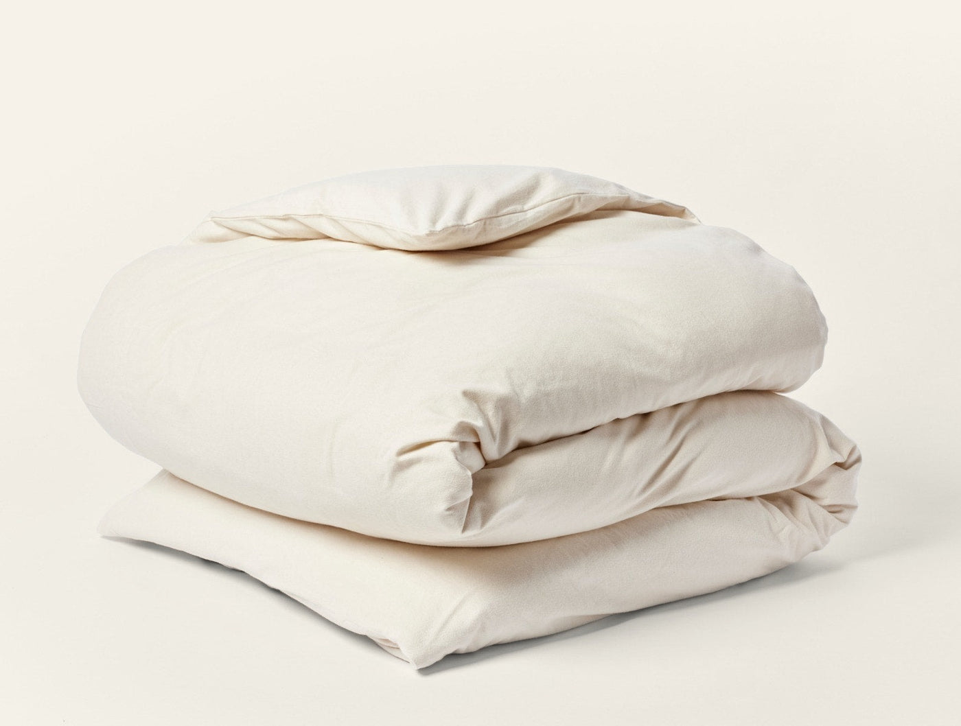 Close-up of folded ivory Coyuchi Cloud Brushed Flannel duvet cover showing soft texture.