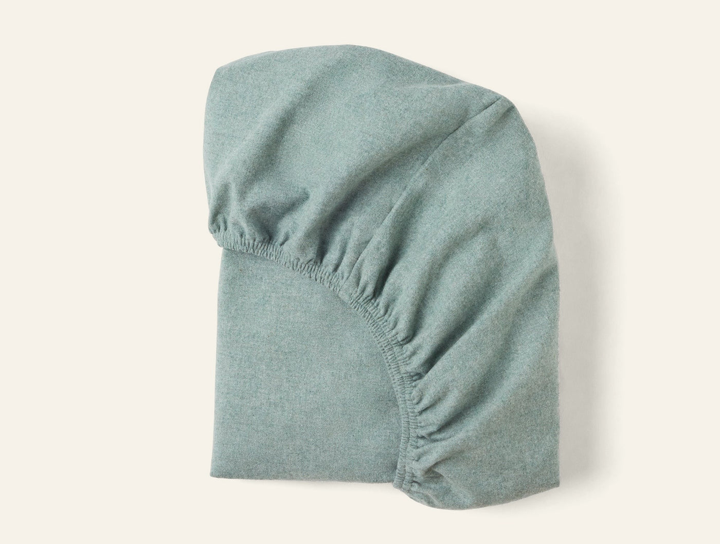 Coyuchi Cloud Brushed Flannel fitted sheet in sage green, folded to show elasticized corners.