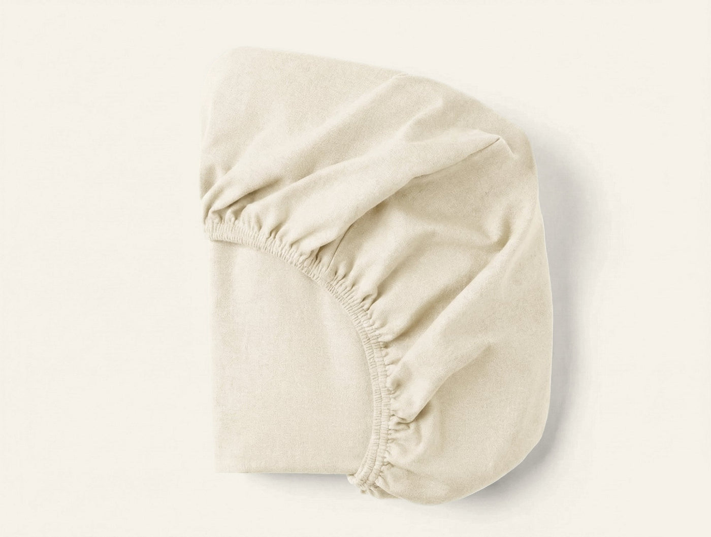 Coyuchi Cloud Brushed Flannel fitted sheet in ivory, elasticated corners visible.