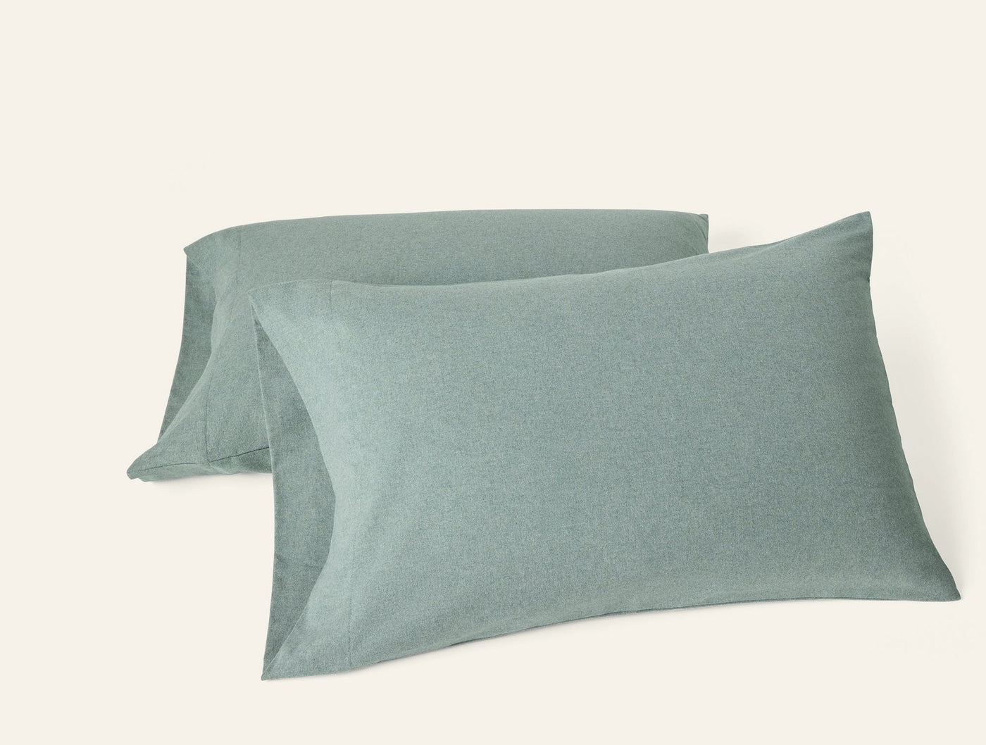 Pair of sage green brushed flannel pillowcases stacked against white background.