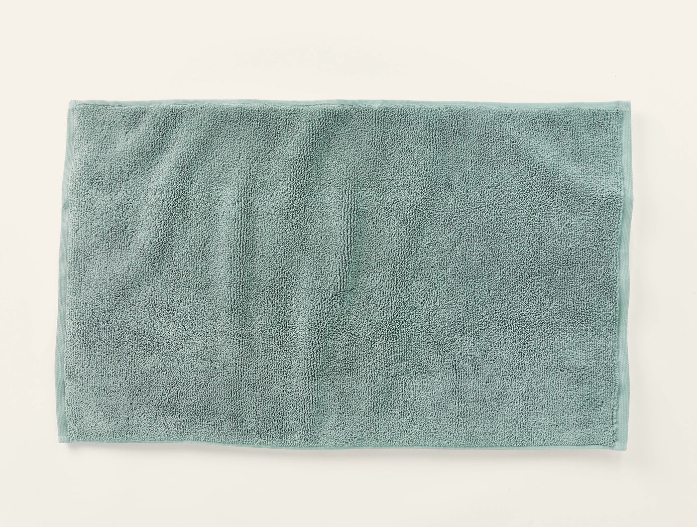 Coyuchi Cloud Loom bath rug in sage green, flat lay showing plush terry texture.