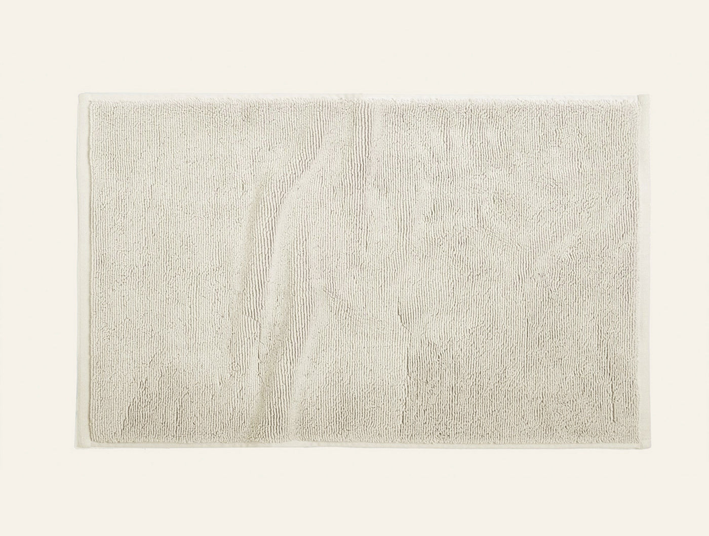 Close-up of Coyuchi Cloud Loom bath rug in ivory, showing plush terry texture and flat border trim.