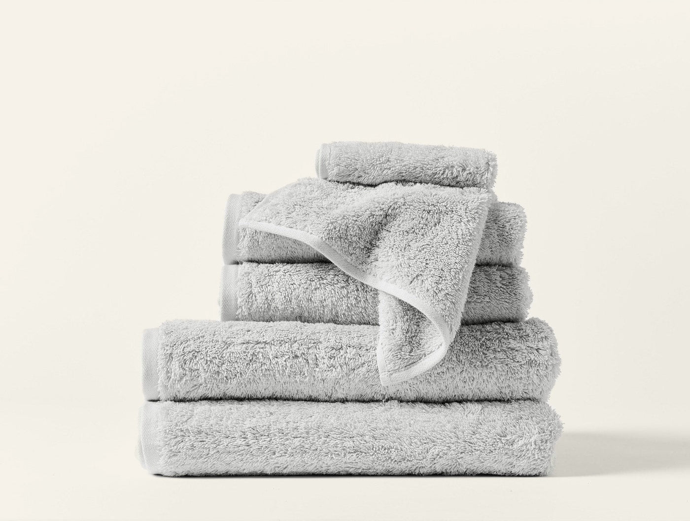 Stacked silver Coyuchi Cloud Loom towels in assorted sizes on white background.
