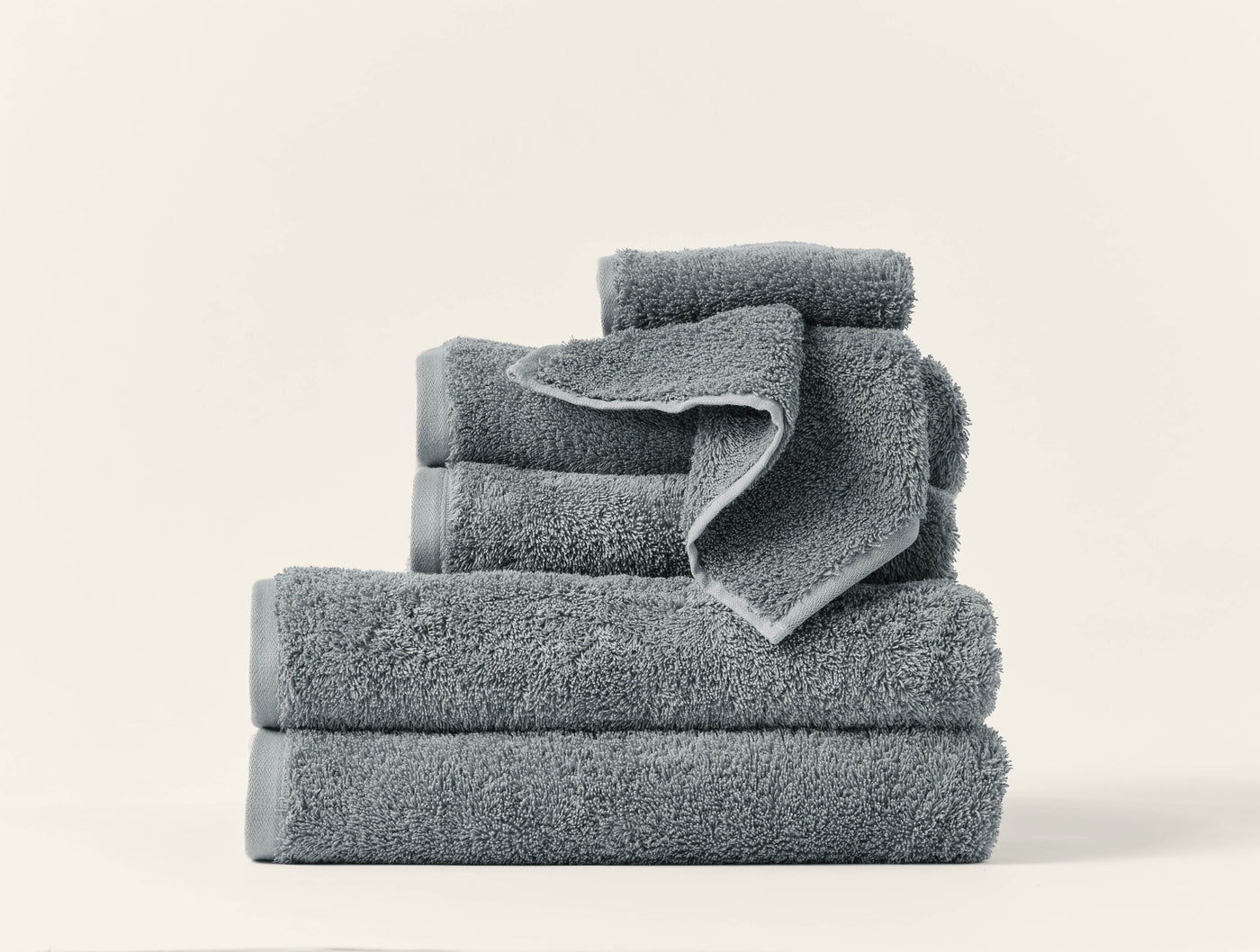 Stacked slate Coyuchi Cloud Loom towels in varied sizes showing plush terry texture.