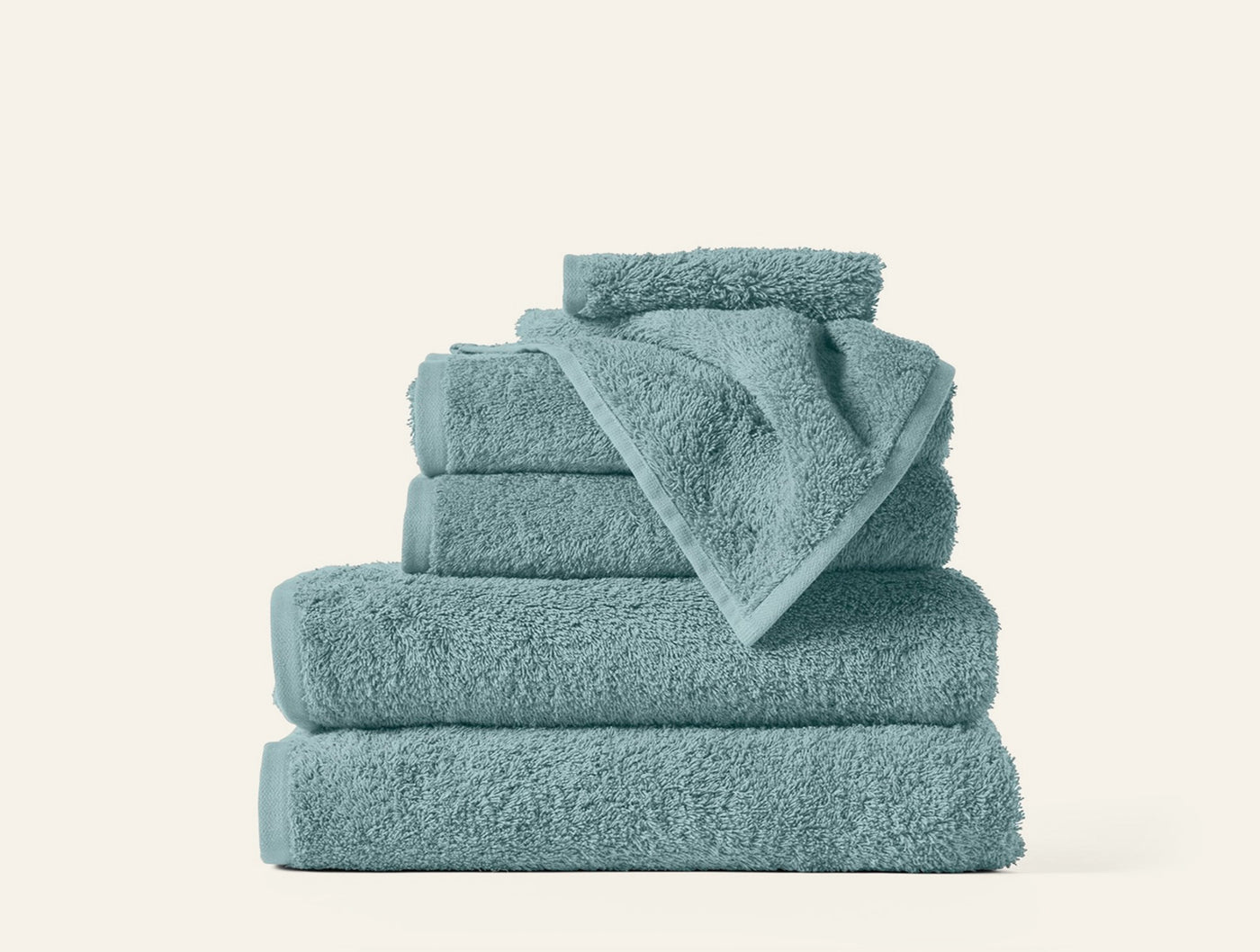 Stack of six seafoam Coyuchi Cloud Loom towels in varied sizes, neatly folded.