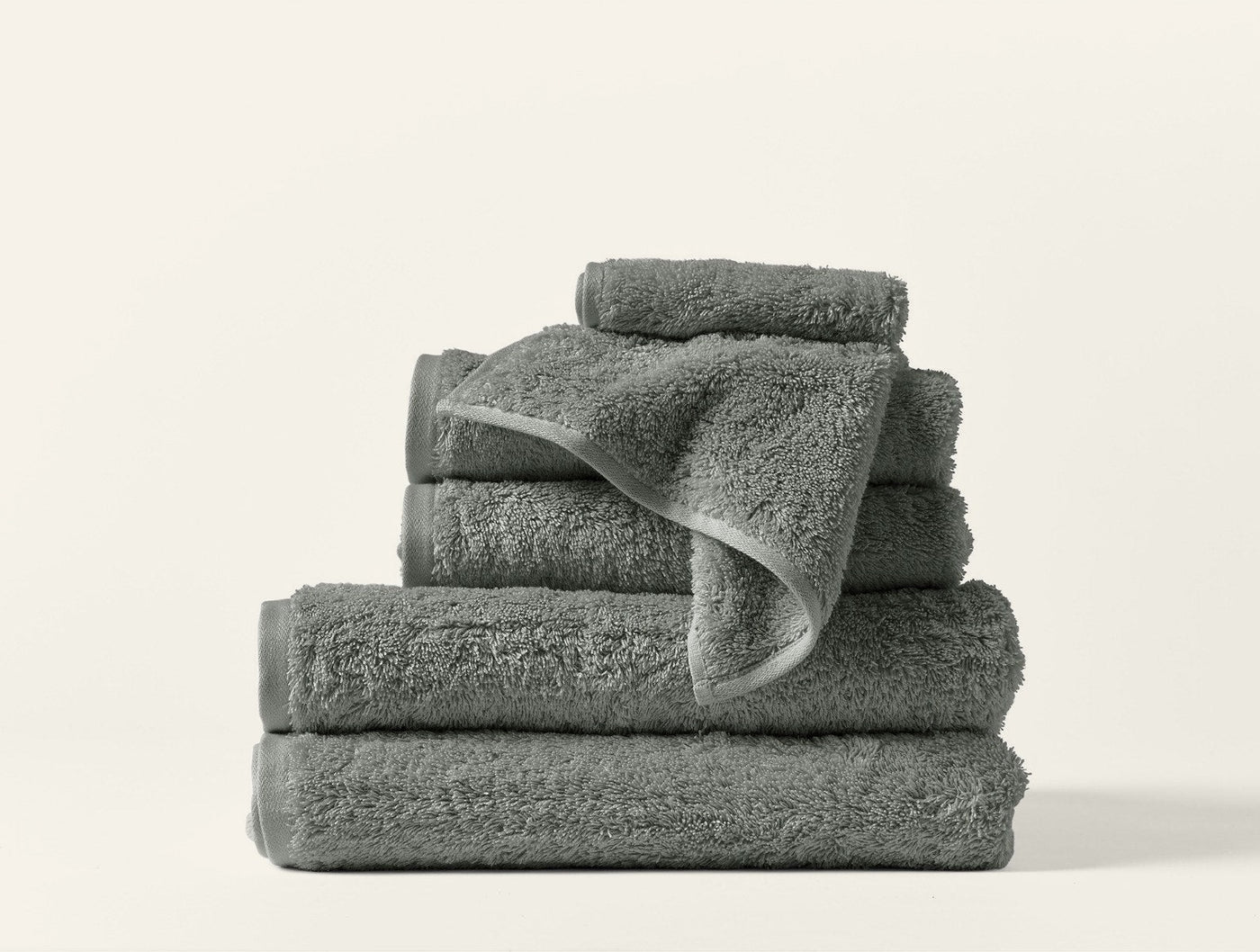 Close-up of stacked sage green Coyuchi Cloud Loom towels showing plush loop texture.