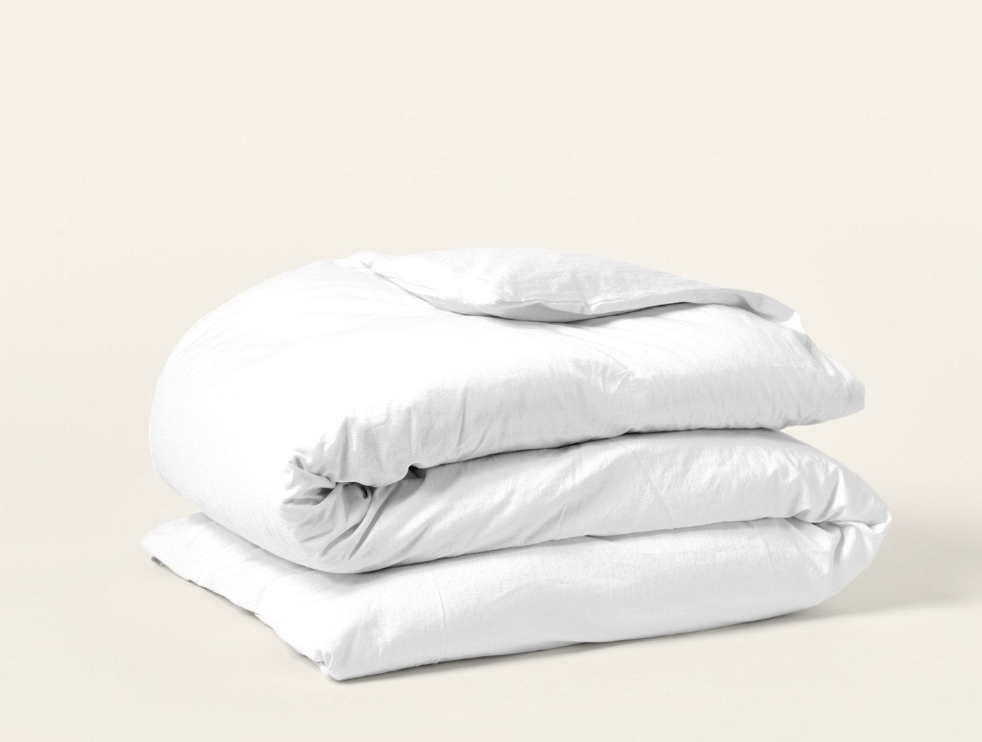 Coyuchi Cloud Soft Sateen duvet cover in white, neatly folded stack on light background.