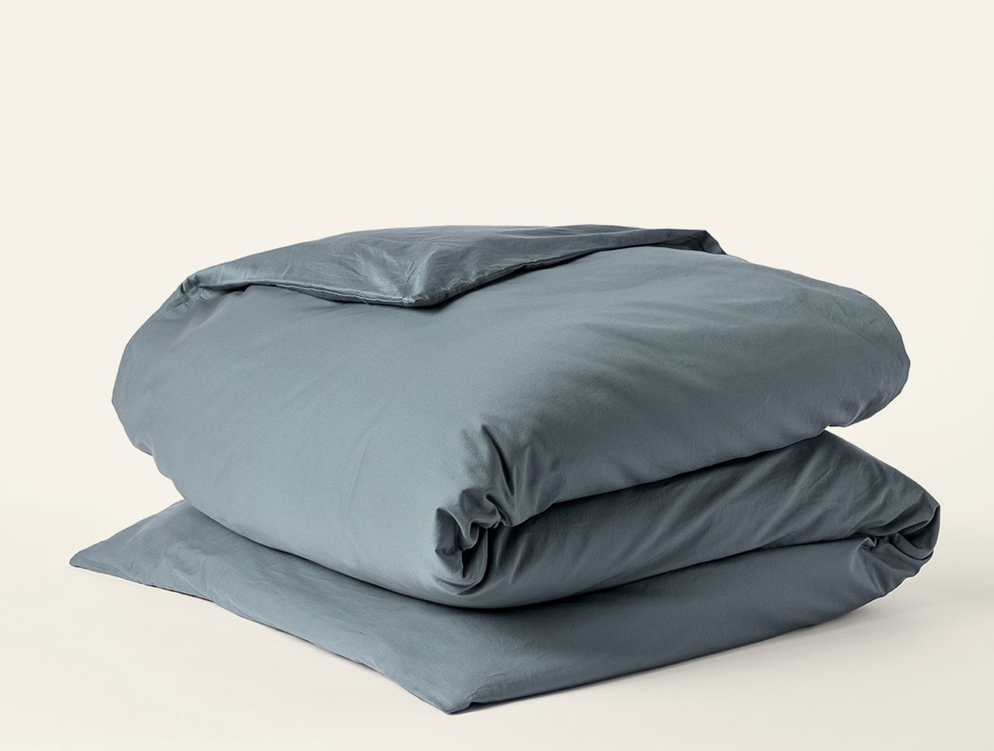 Coyuchi Cloud Soft Sateen duvet cover folded in slate blue, showing smooth sateen finish.
