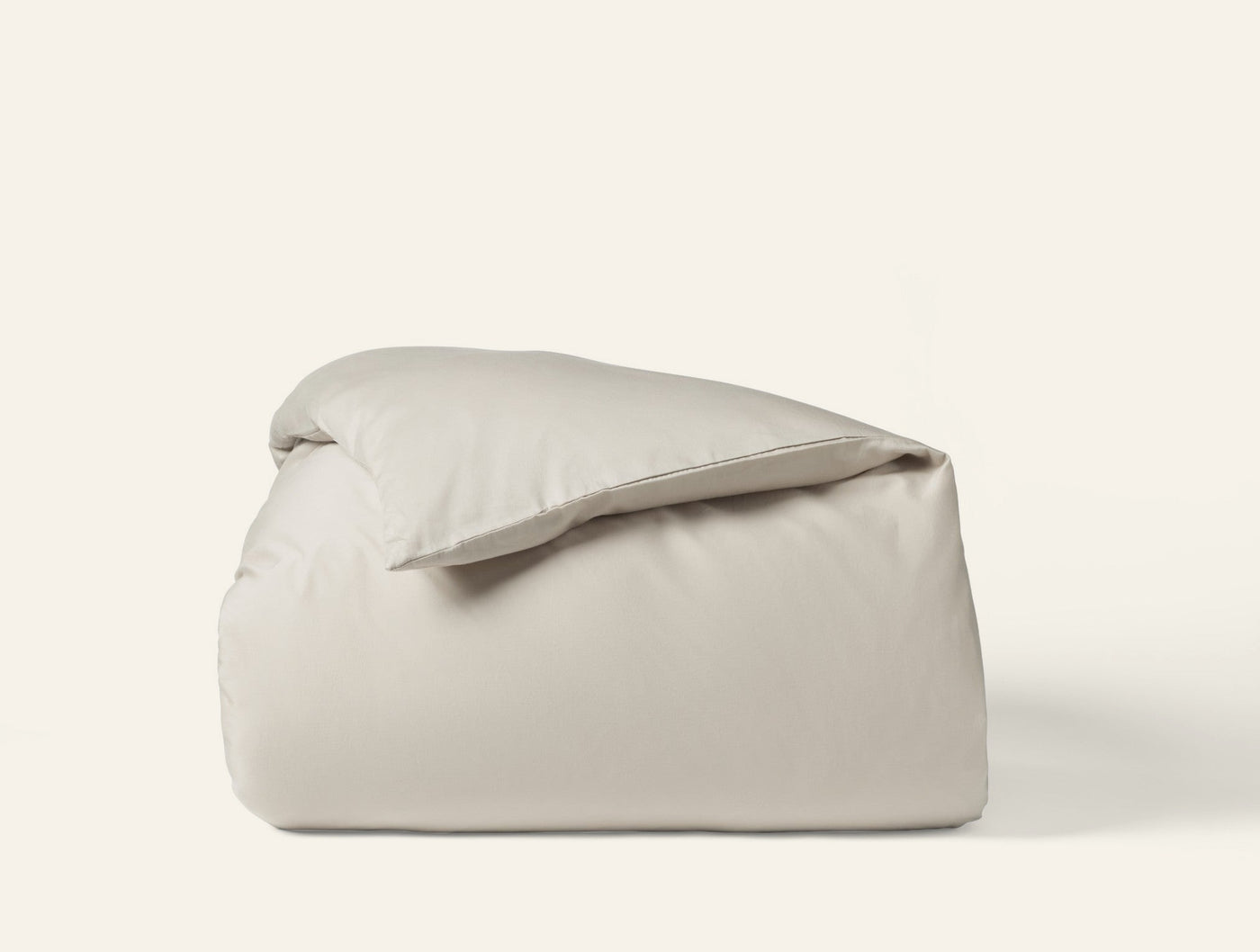 Ivory sateen duvet cover folded and stacked, showing smooth matte finish.