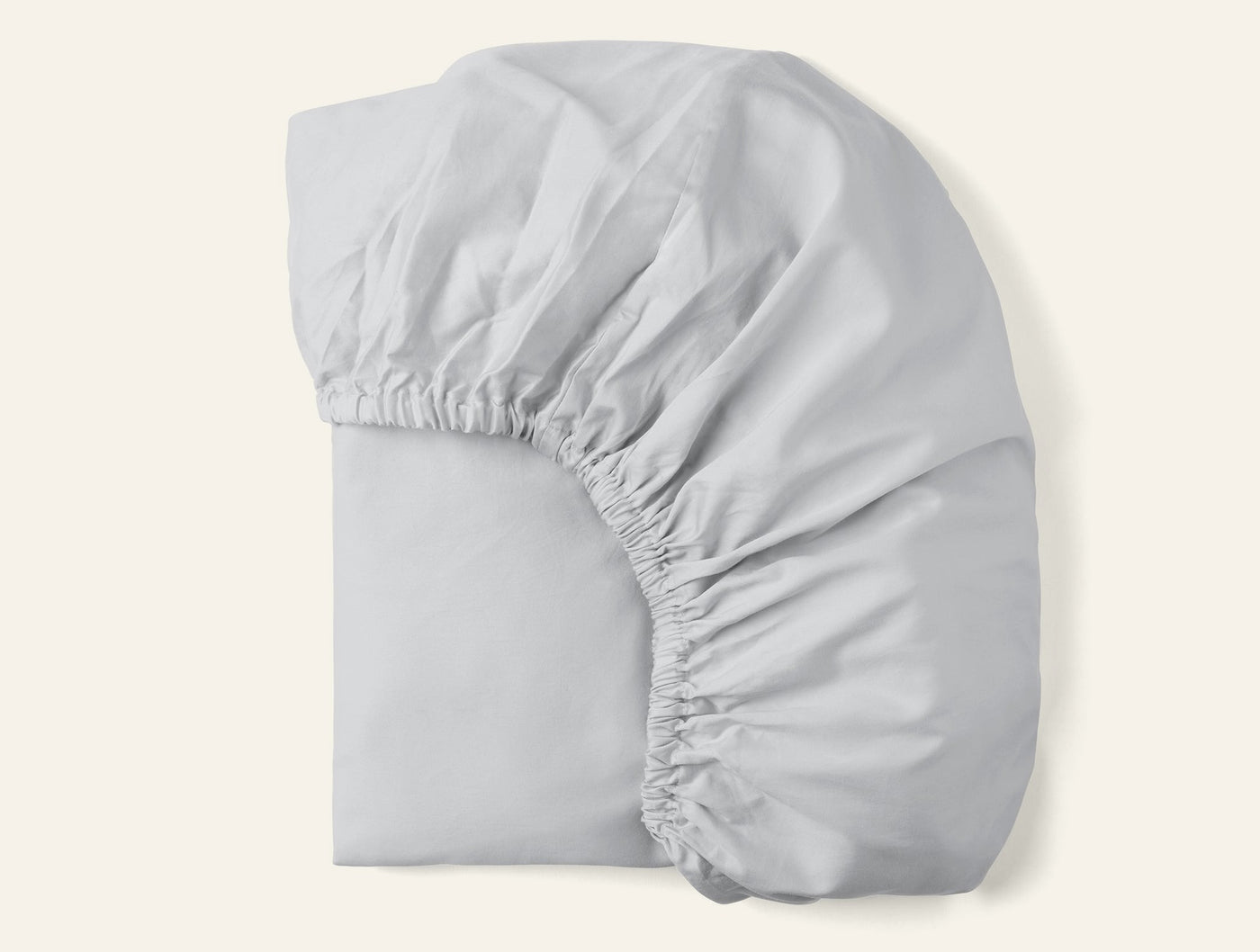 Coyuchi Cloud Soft Sateen fitted sheet folded, silver white with visible elasticized corners.