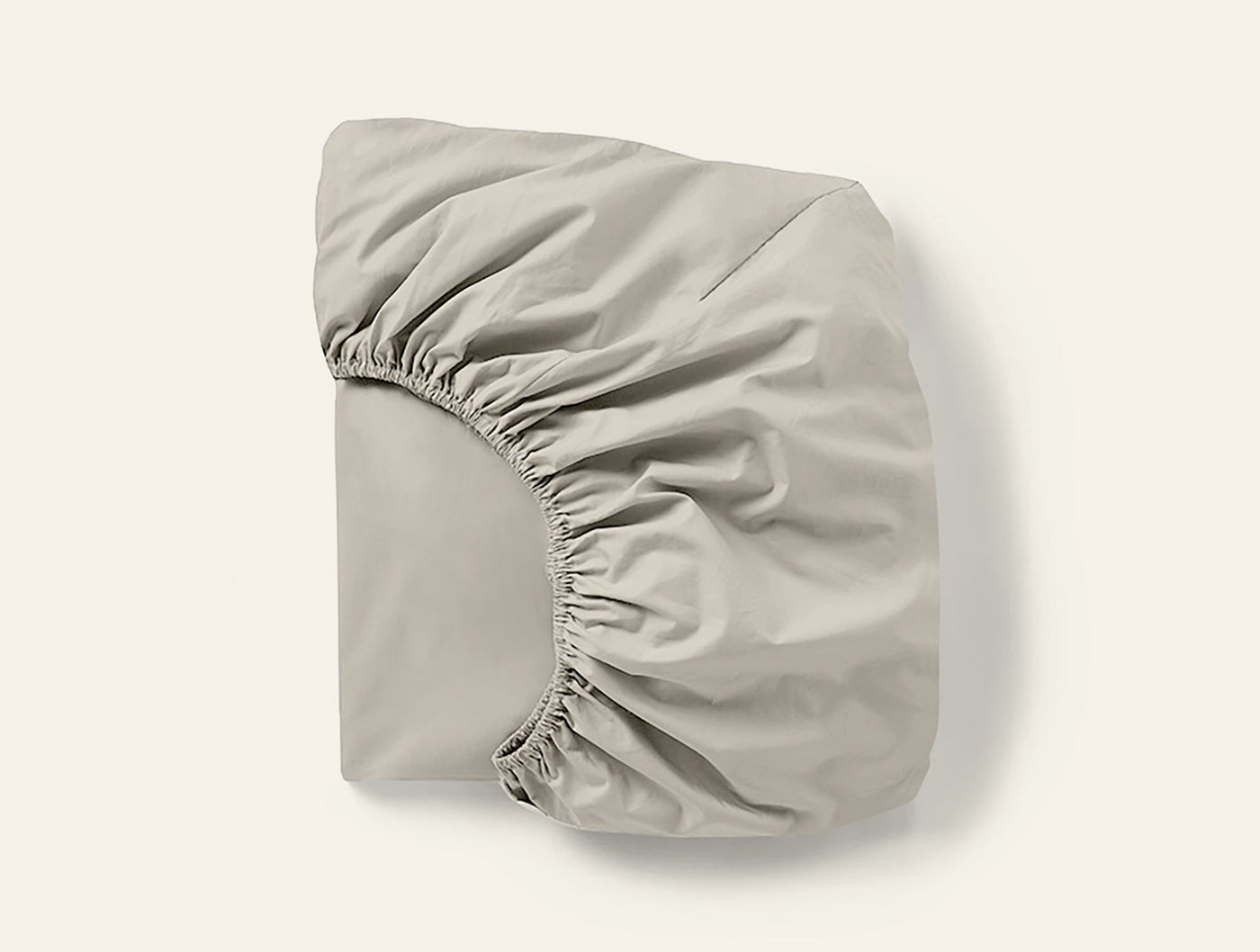Coyuchi Cloud Soft Sateen fitted sheet folded, showing elasticized corner detail in pebble.