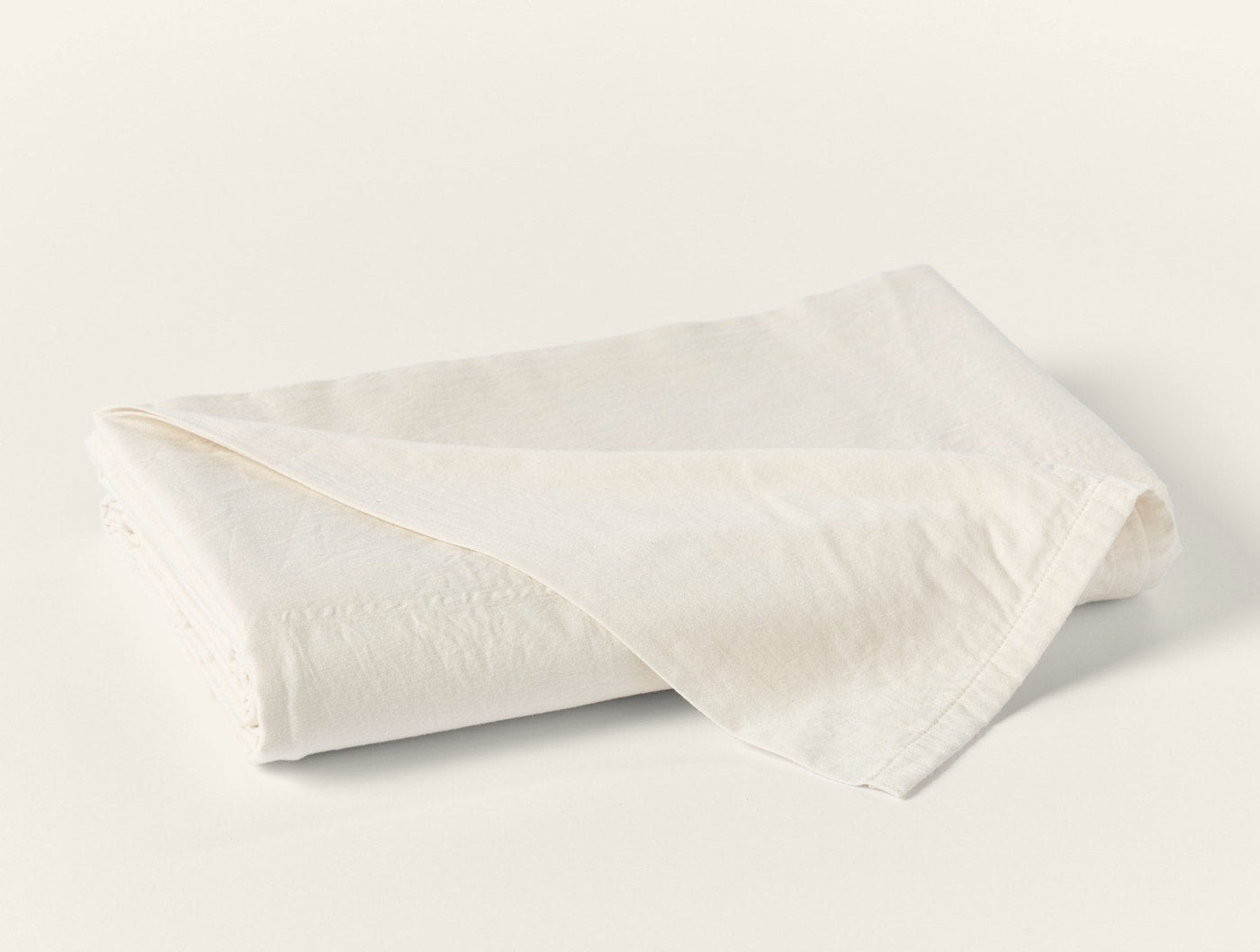 Coyuchi Cloud Soft Sateen flat sheet folded in ivory, showing smooth sateen finish.