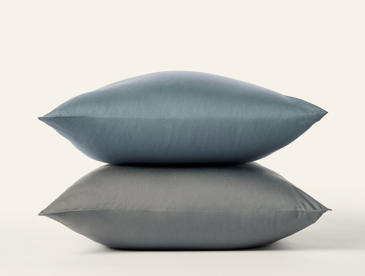 Two slate blue Coyuchi Cloud Soft Sateen pillowcases stacked against a white background.
