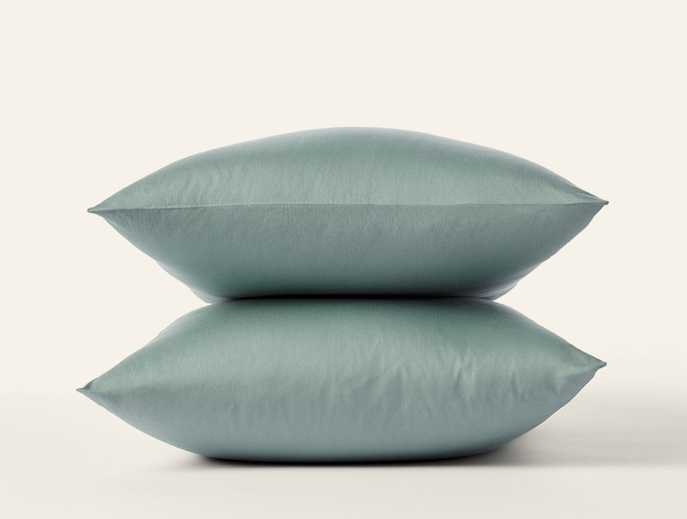 Two stacked sage Coyuchi Cloud Soft Sateen pillowcases against a white background.