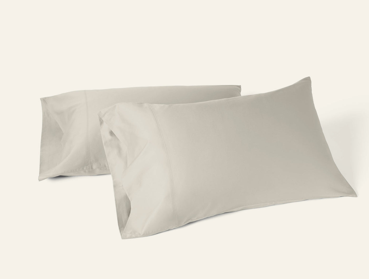 Two Coyuchi Cloud Soft Sateen pillowcases in stone, overlapping on white background.