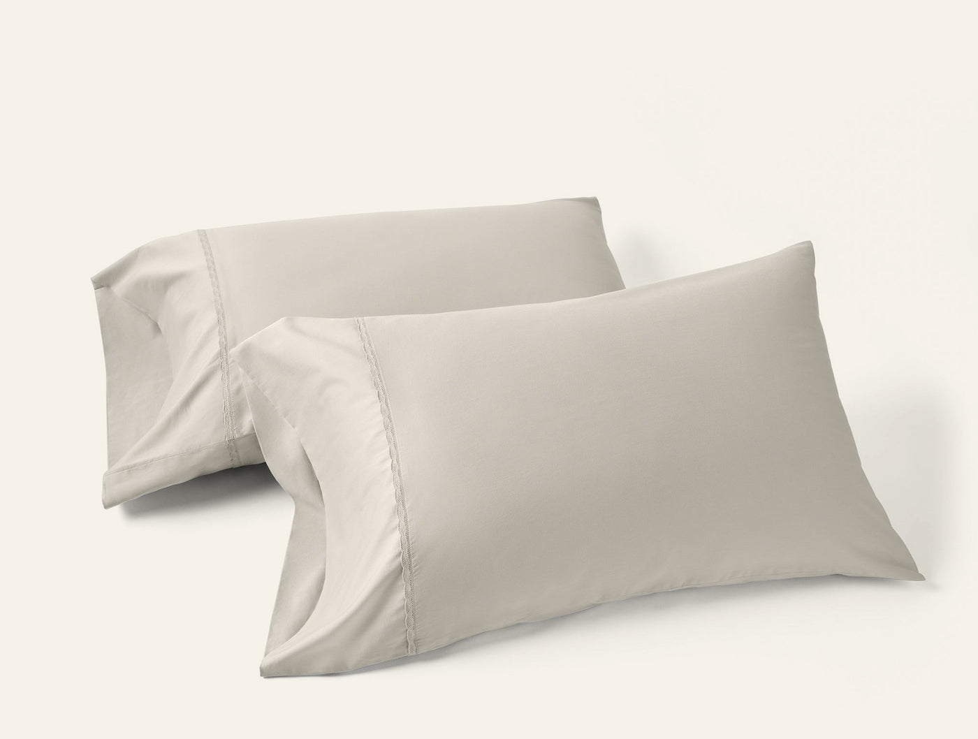 Two Coyuchi Cloud Soft Sateen pillowcases in stone, stacked at an angle on white background.