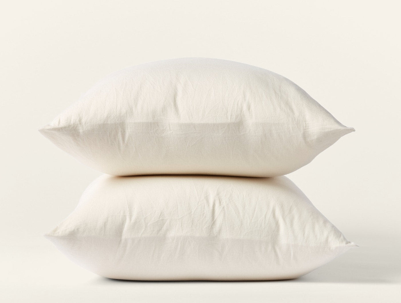 Two ivory Coyuchi Cloud Soft Sateen pillowcases stacked, showing smooth finish and plump fill.