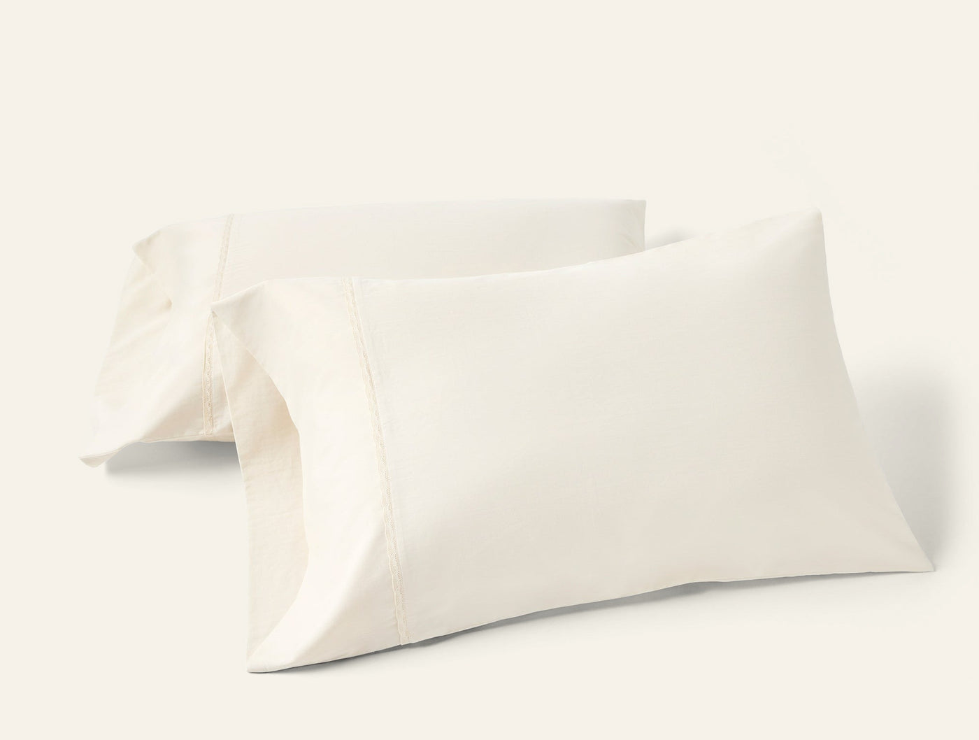 Two ivory Coyuchi Cloud Soft Sateen pillowcases stacked at an angle on a white background.