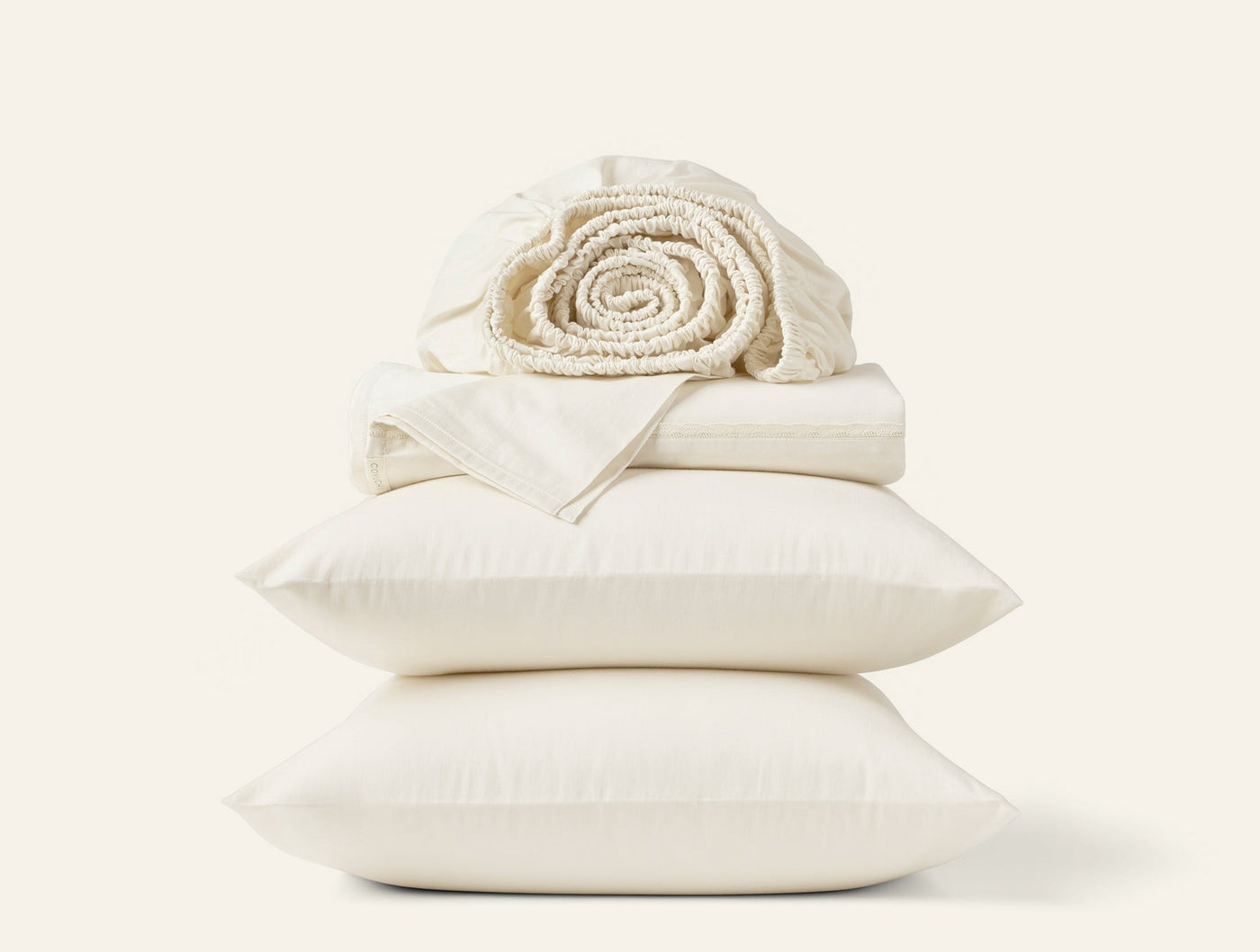 Ivory sateen sheet set stacked with rolled waffle blanket atop two pillowcases.