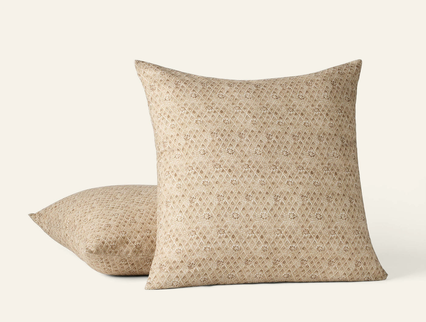 Coyuchi Coral Bell Print pillow covers in sand, small geometric floral repeat pattern, two sizes stacked.