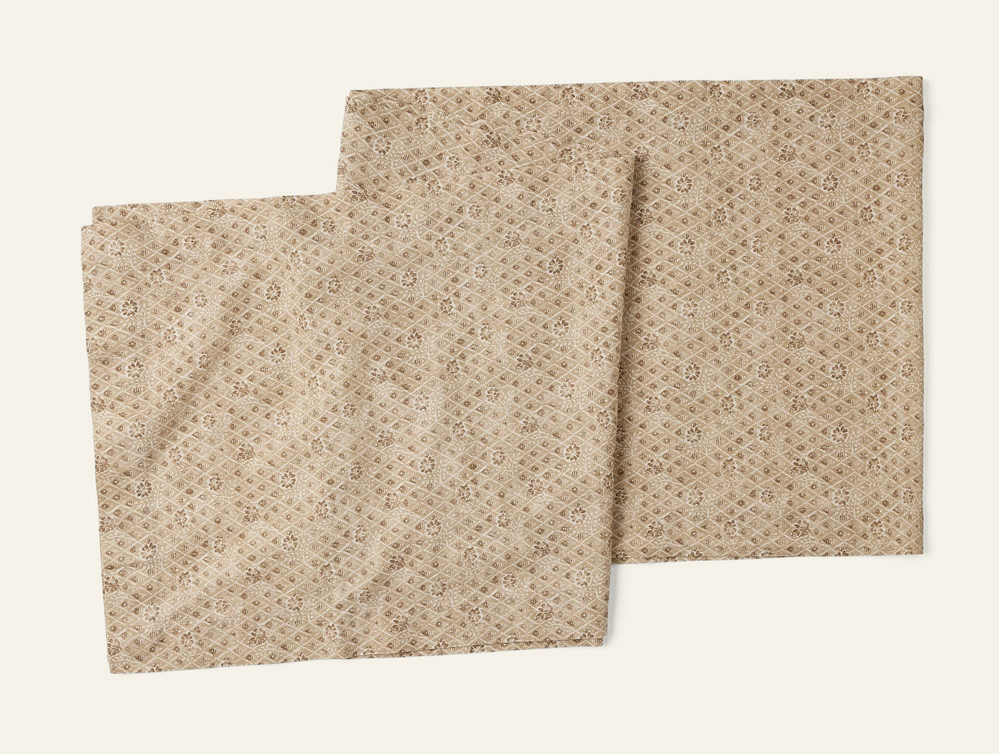 Two Coyuchi Coral Bell Print table runners in sand, showing geometric pattern detail.