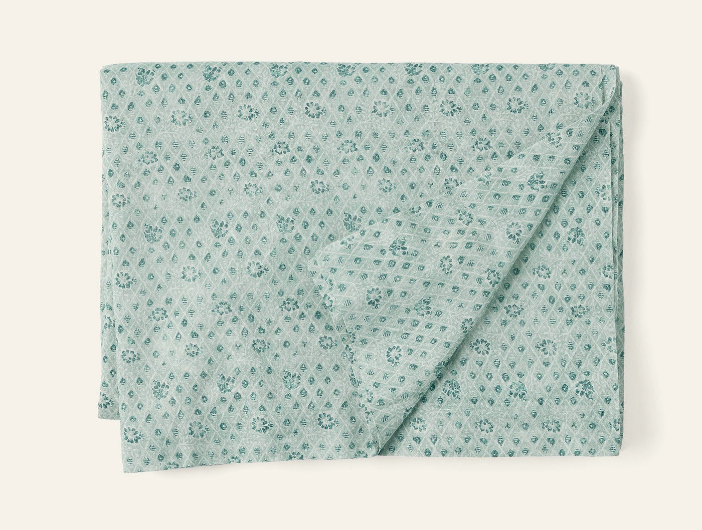 Coyuchi Coral Bell Print tablecloth folded, sage green with tonal floral diamond print.