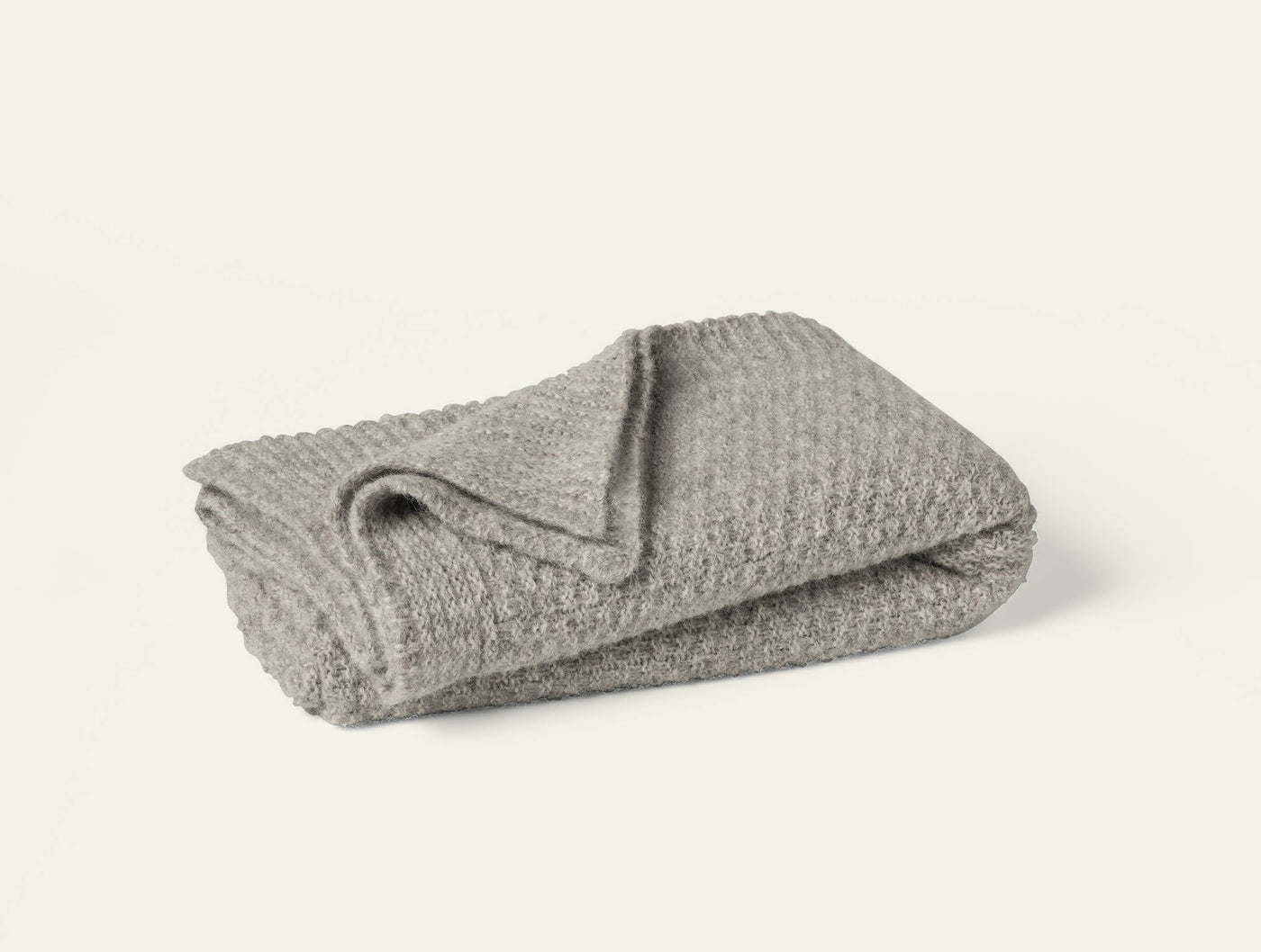 Folded taupe alpaca-cotton knit throw with textured waffle-like pattern, neutral tone.