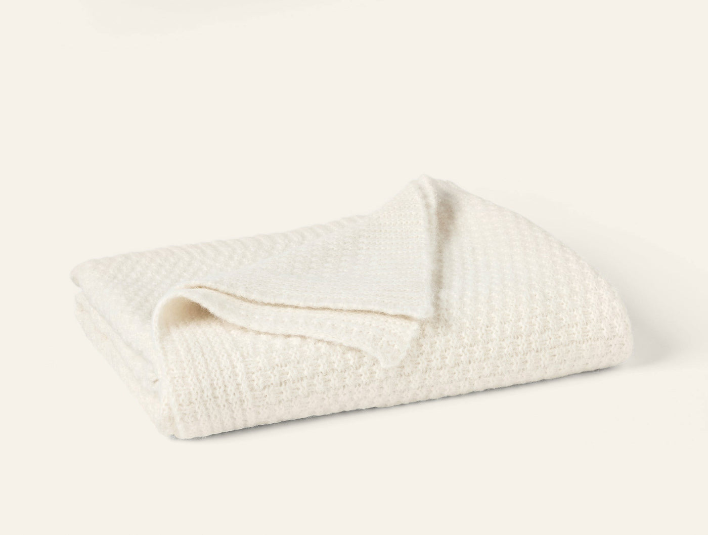 Close-up of ivory alpaca cotton knit throw, folded to show waffle texture detail.