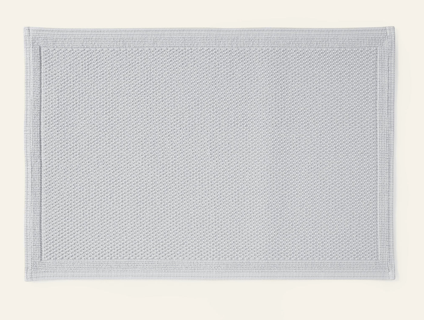 Coyuchi Cove bath rug in silver, showing textured weave and bordered edge detail.