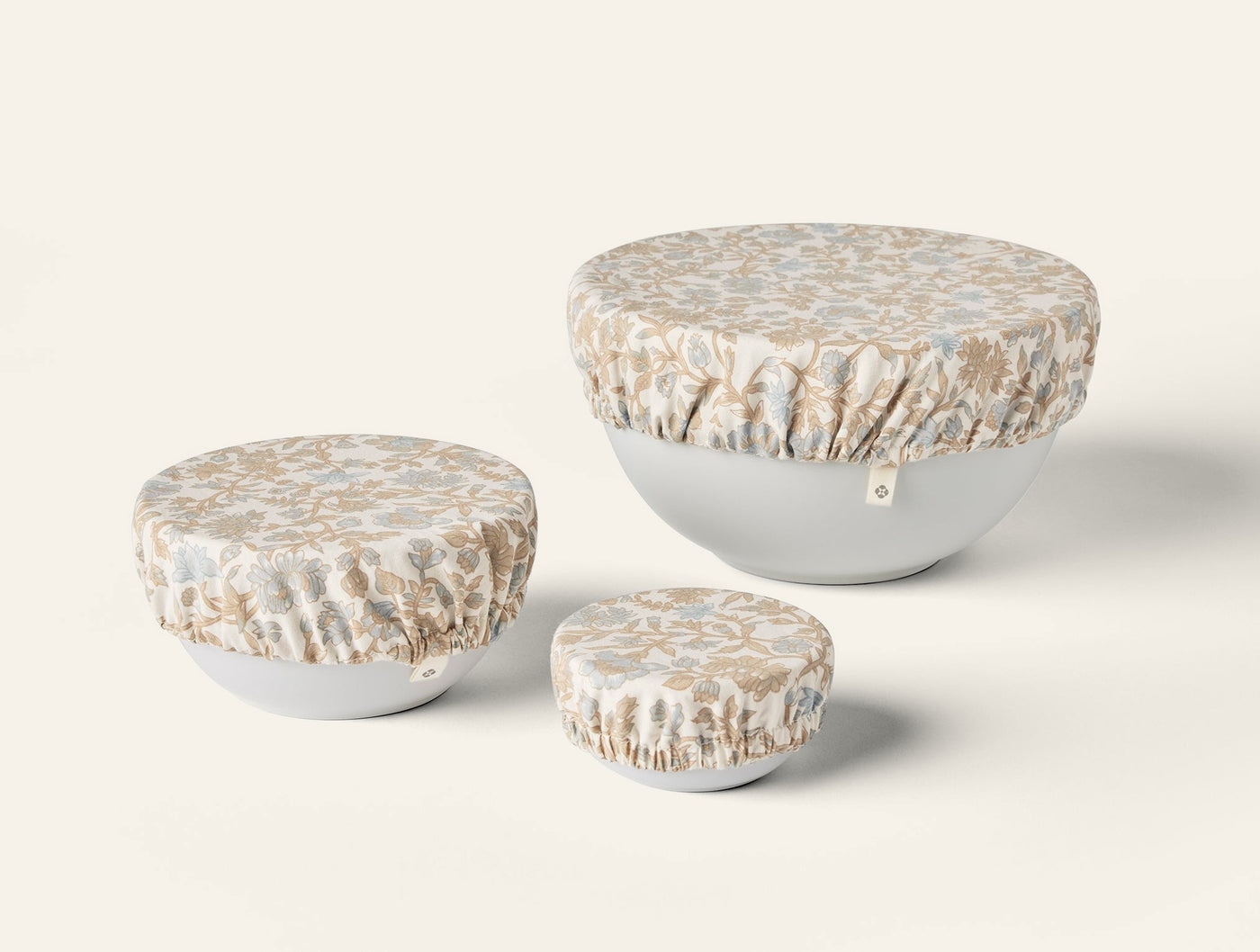 Coyuchi Conserve bowl cover set in three sizes, ivory floral print fabric stretched over white bowls.