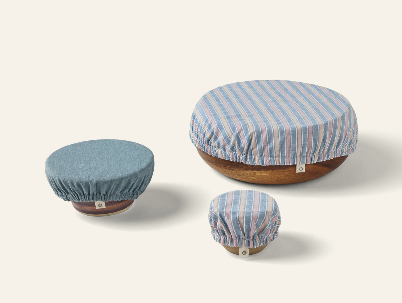 Three Coyuchi Conserve bowl covers in blue stripe linen, shown on wooden bowls in small, medium, large sizes.