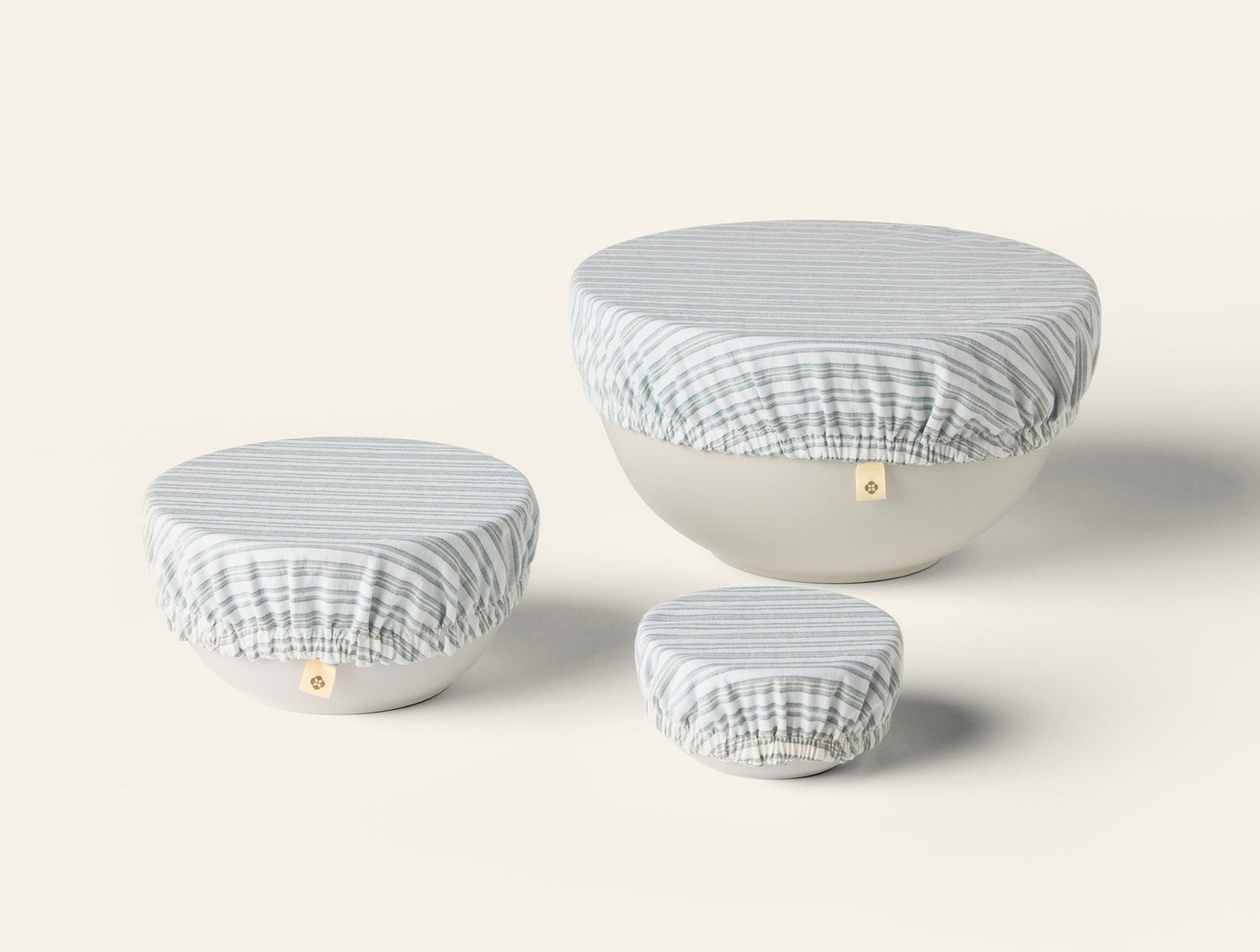 Three Coyuchi Conserve bowl covers in blue stripe, shown on small, medium, and large bowls.