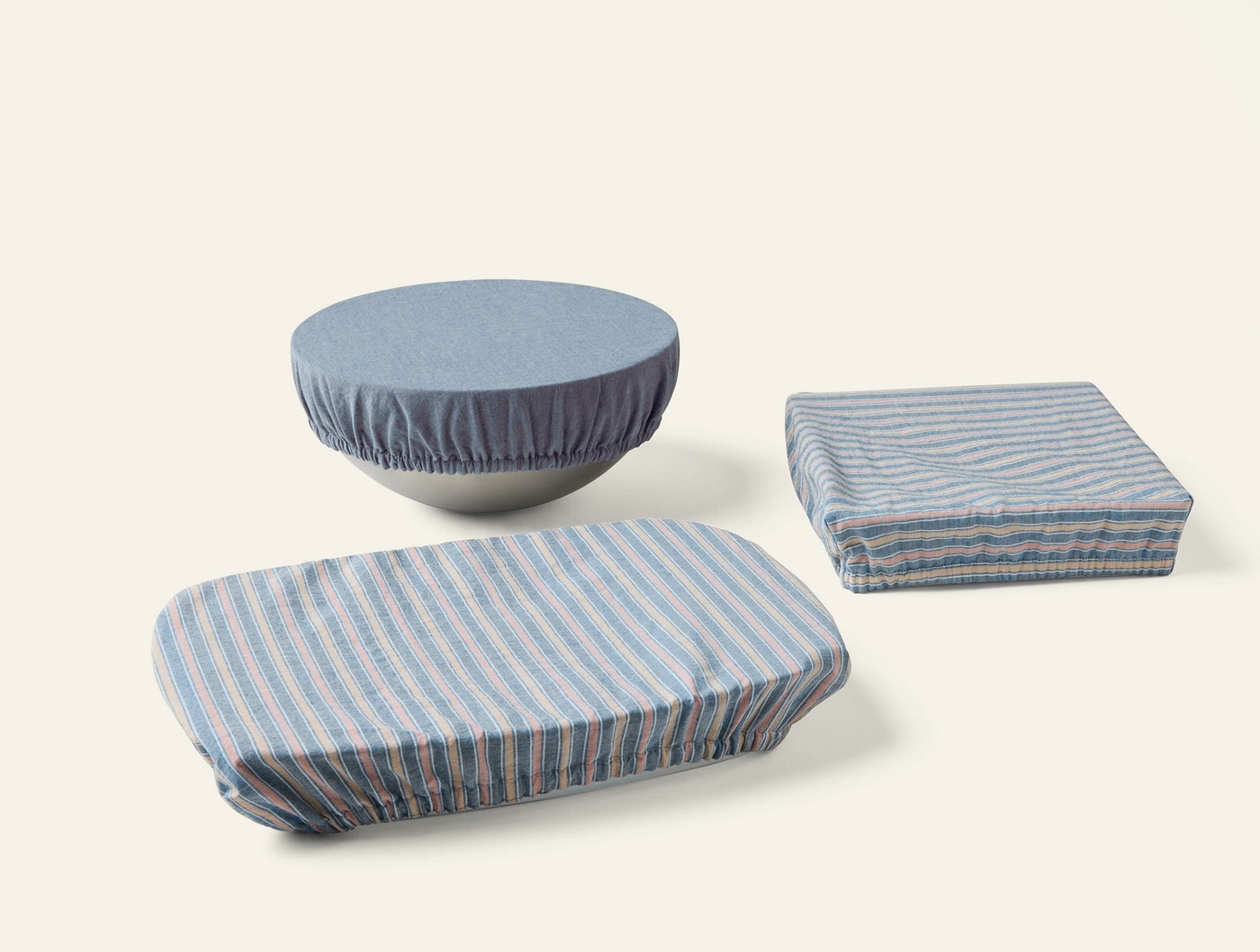 Coyuchi Conserve dish cover set in blue stripe and solid blue, styled on three dishes.