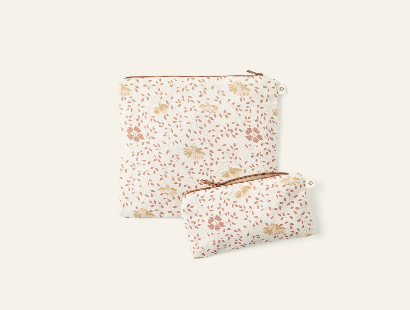 Two Coyuchi Conserve snack bags in ivory floral print with rust zipper pulls, large and small sizes.